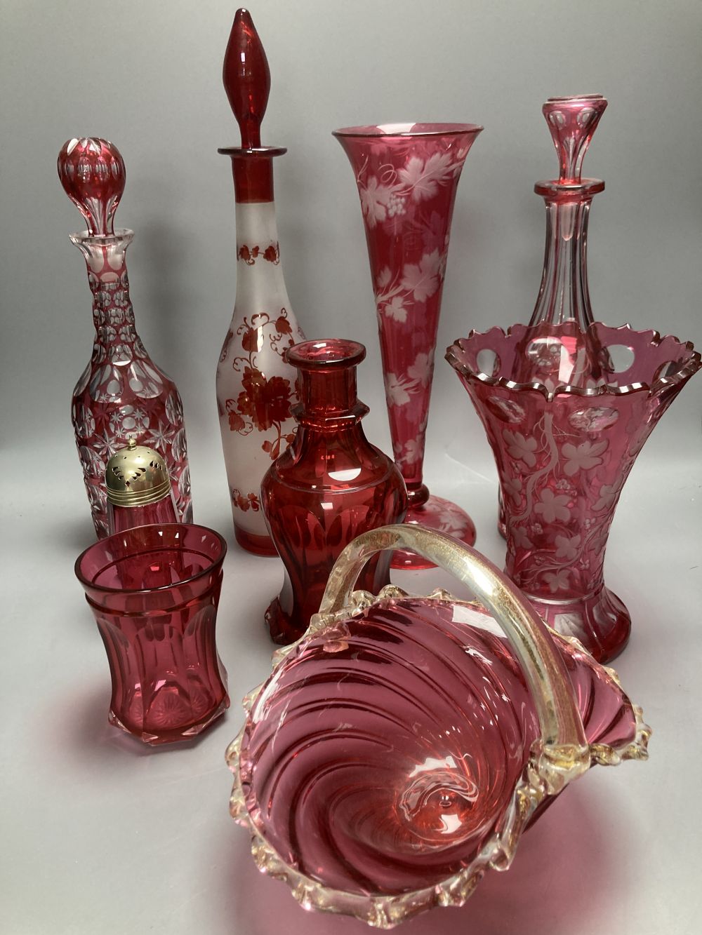 A collection of nine pieces of cranberry and ruby coloured glass, including a pair of decanters, two vases and a carafe and tumbler